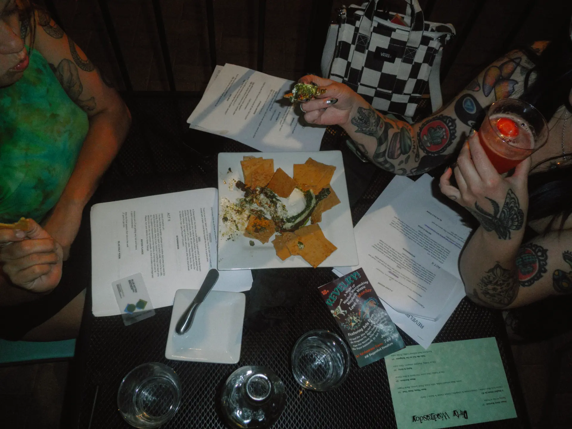 Overhead shot of a shared appetizer, drinks and printed programs on the table