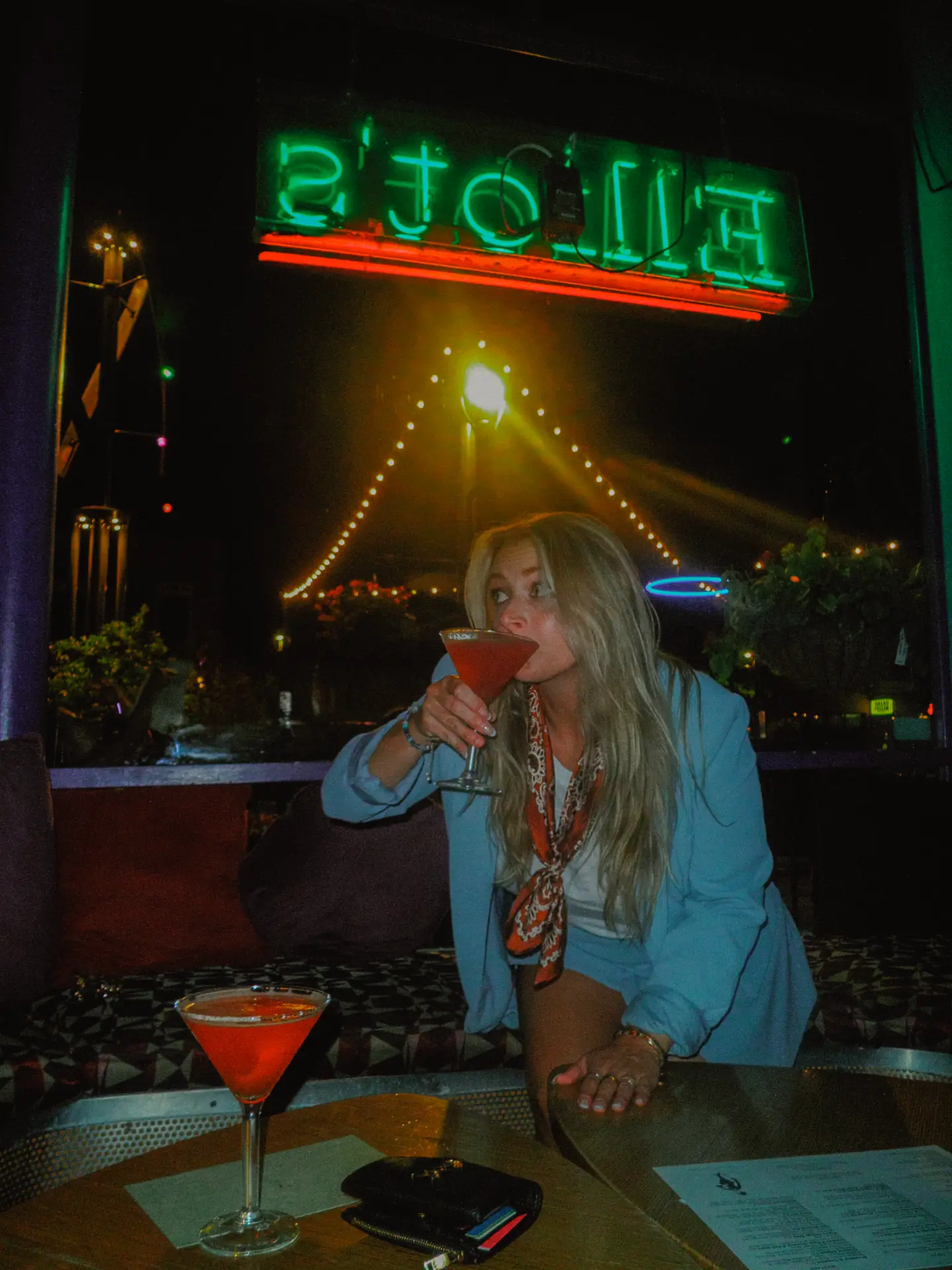 Guest sipping a martini beneath the green Elliot's neon sign