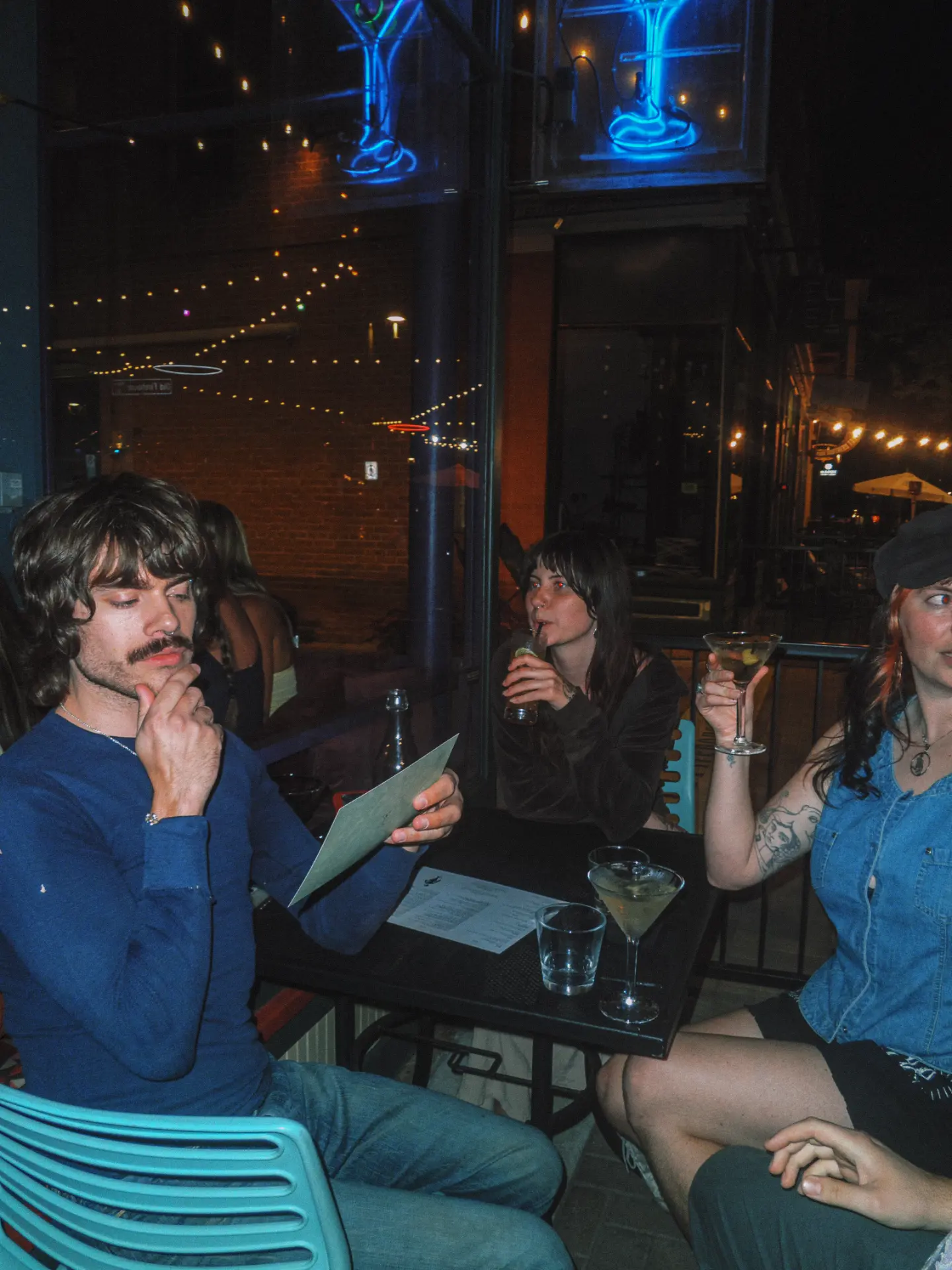 Guest in a blue shirt reading the menu on the patio at night