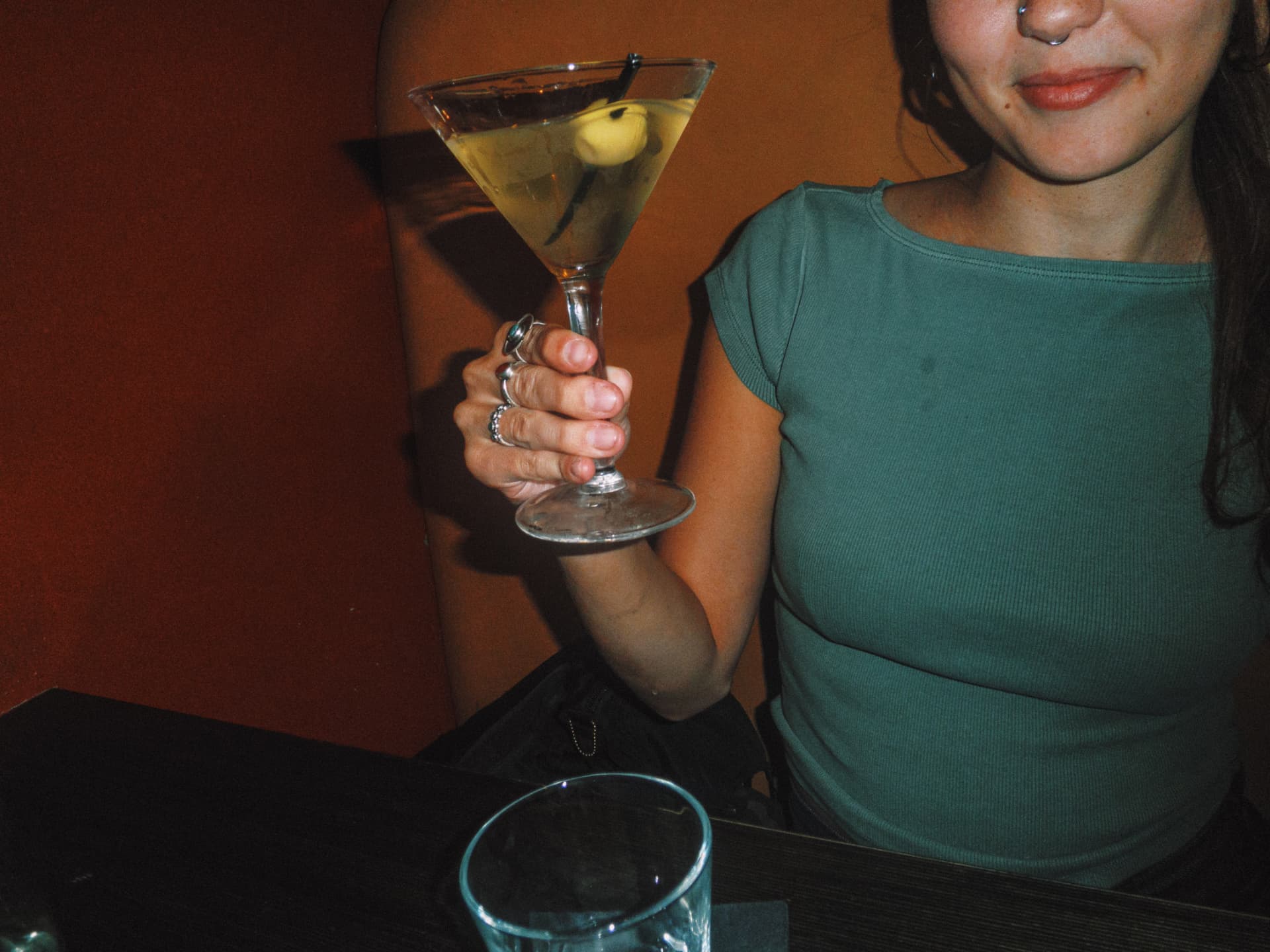 Guest holding a lychee martini against the red wall