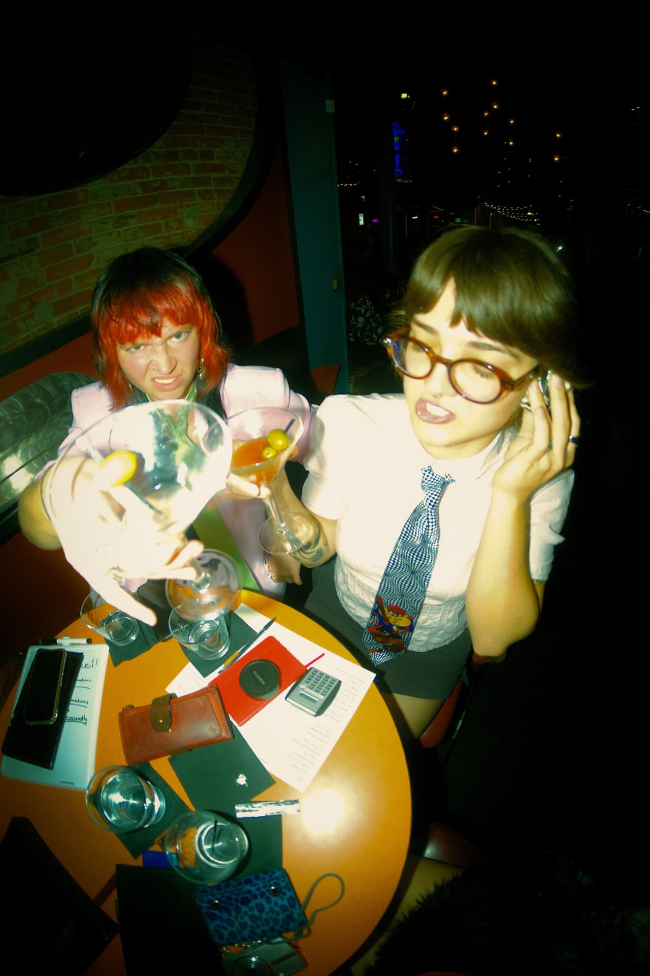 Two guests in costume raising martinis over a crowded table