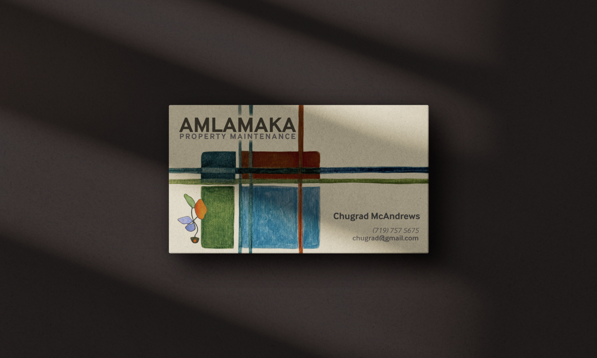 AMLAMAKA business card on a dark surface with shadow